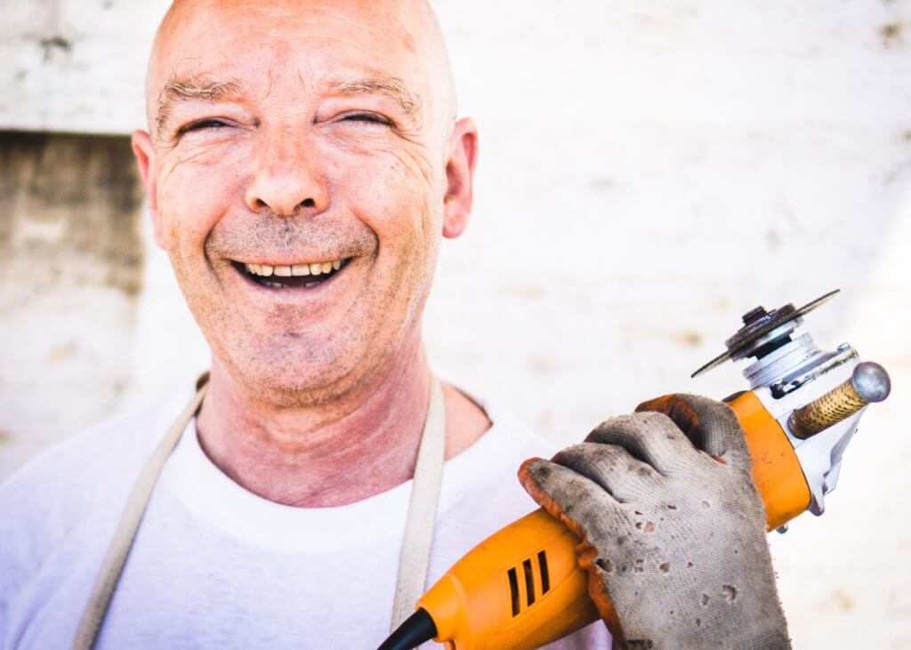 A smiling middle-aged man holds up a disc cutter