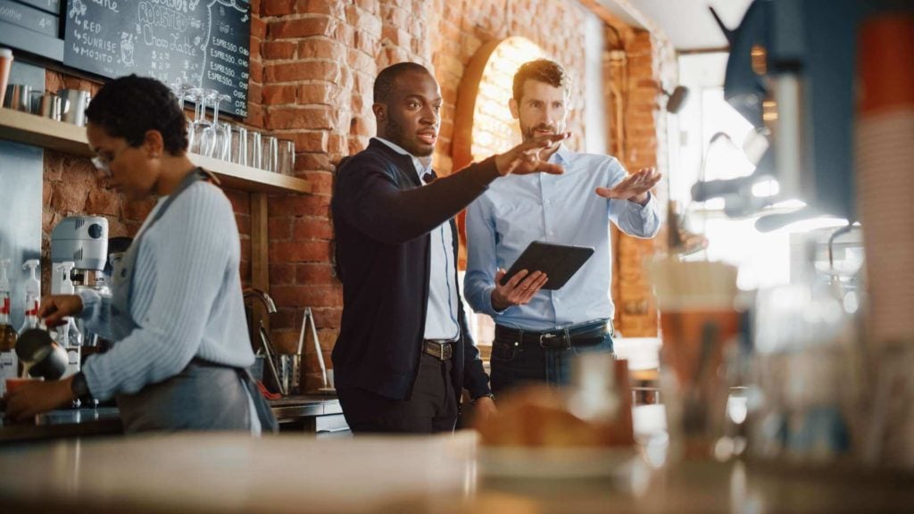 A restaurant manager discusses business details with a shift manager.