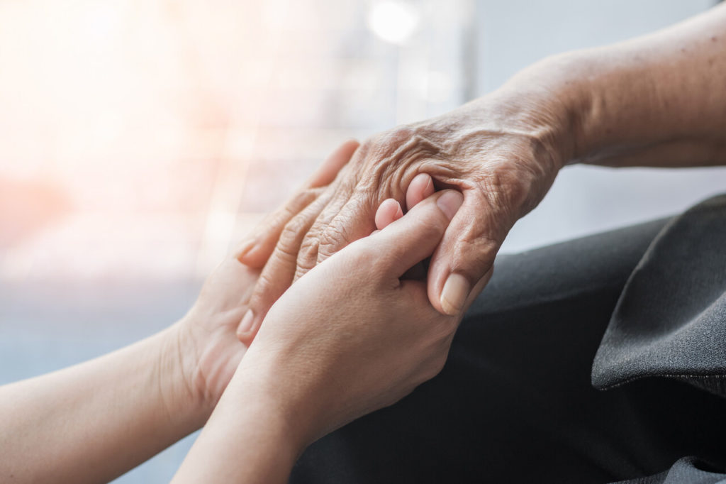 homecare staff member is holding the hand of a patient