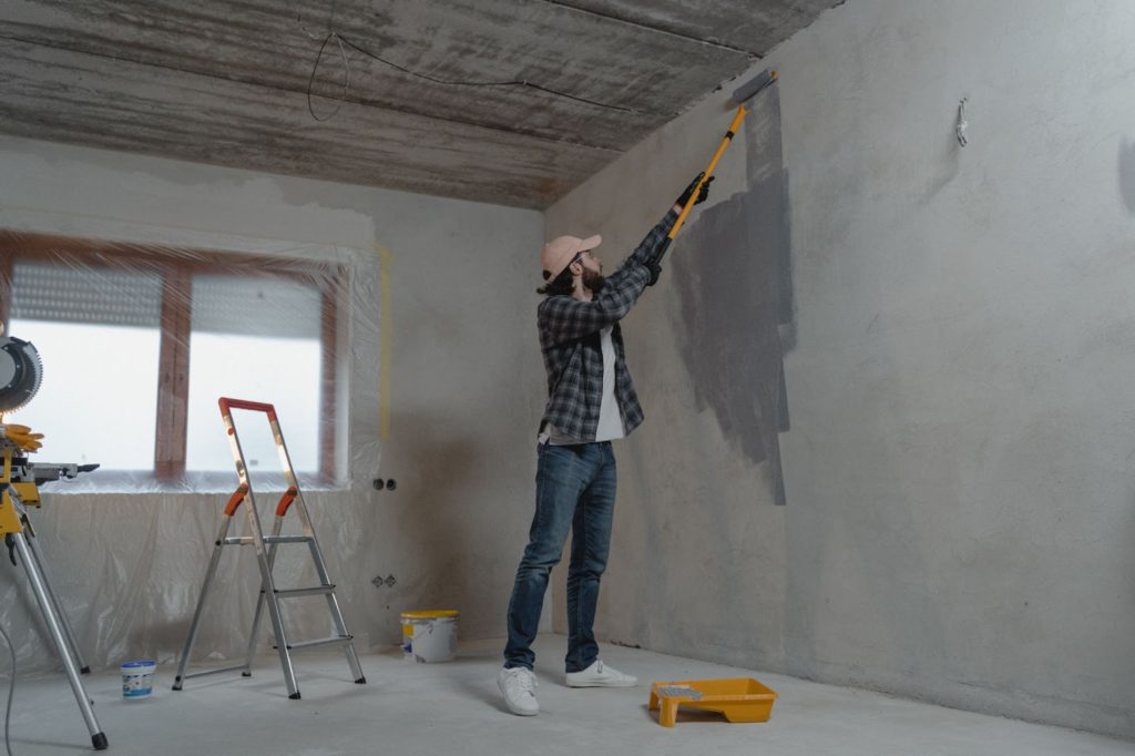 A man painting a wall inside a building.