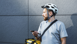 Delivery guy with a helmet holding a cell phone