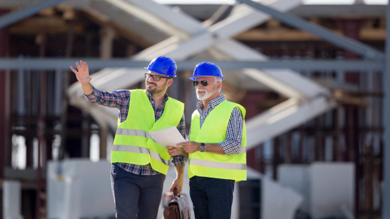 A construction manager and inspector engage in horizontal communication on a construction site