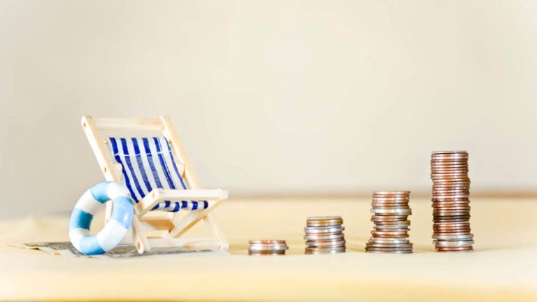 A beach chair sits next to stacks of coins illustrating vacation time vs pto