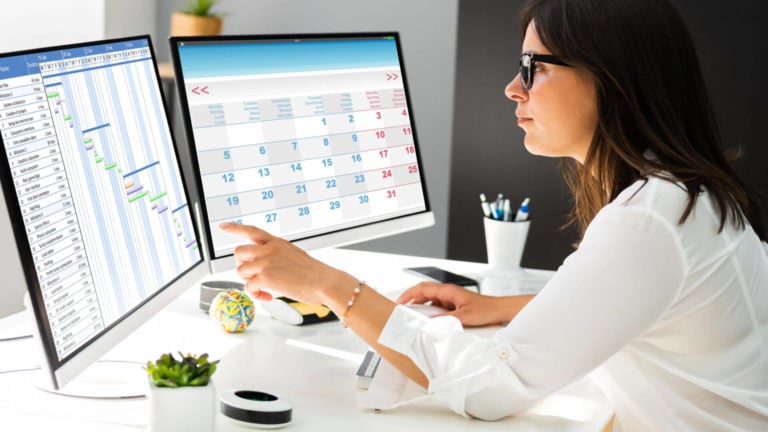 A manager sits in front of a digital employee schedule to manager her staff’s time off requests.