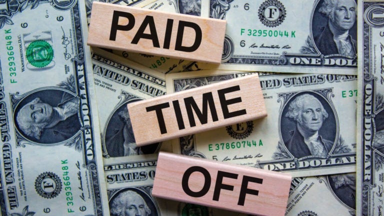 Wooden blocks on a background of US dollar bills illustrating PTO payout laws by state