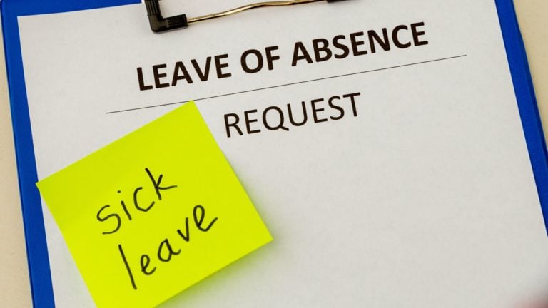 A sticky note on a clipboard reads “sick leave”