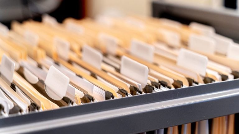 Employee personnel files hang in a filing cabinet