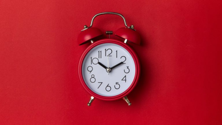 A red old-fashioned alarm clock on a red background