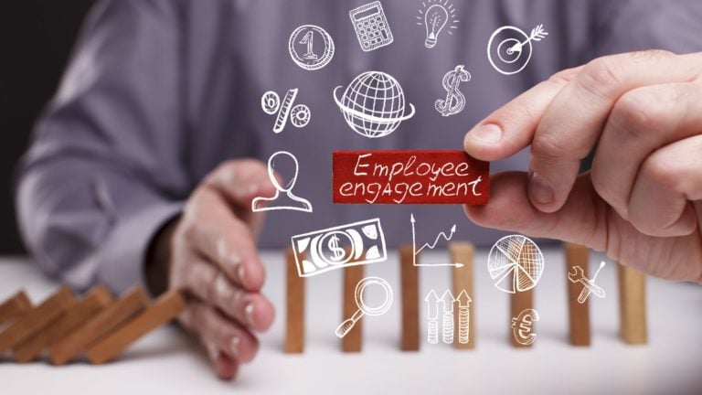 Young businessman holds a domino block with the word: Employee engagement