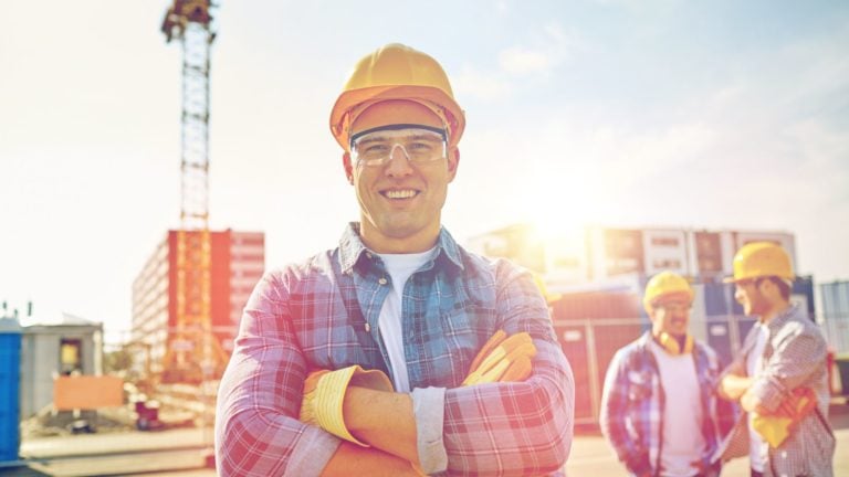 Happy workers stand on a construction site