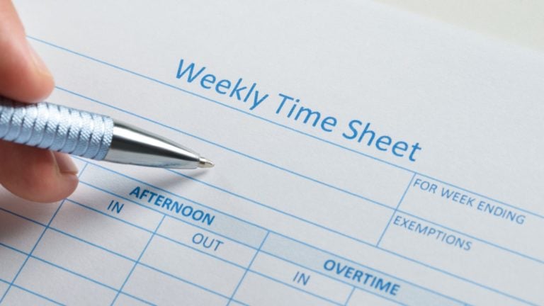 Close-up of a hand holding a pen over a blank weekly time sheet