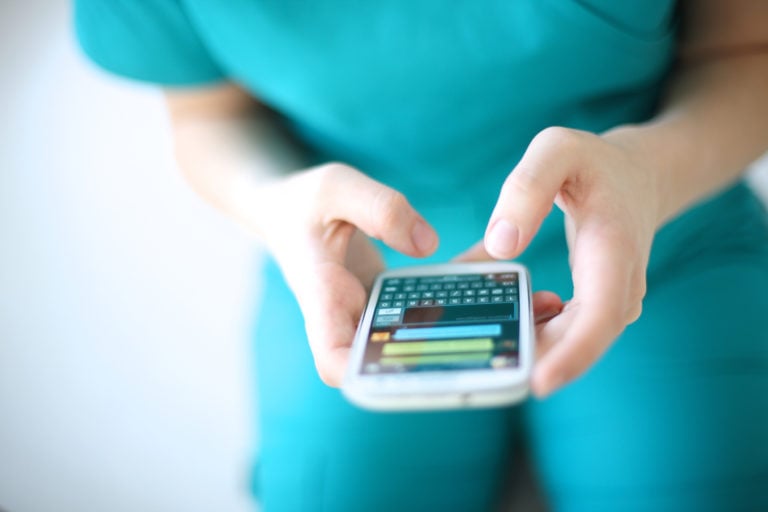 Hands of young woman sending text message from smart phone