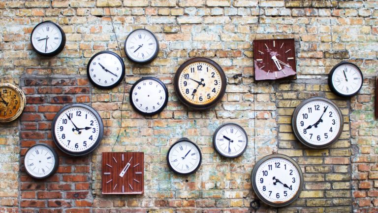 A brick wall full of clocks
