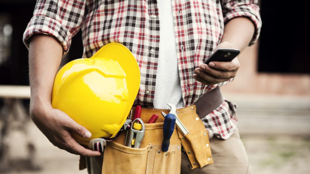 Closeup of a carpenter looking at his phone at work