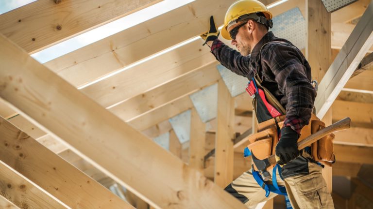 Construction worker in the roof of a wooden housing frame