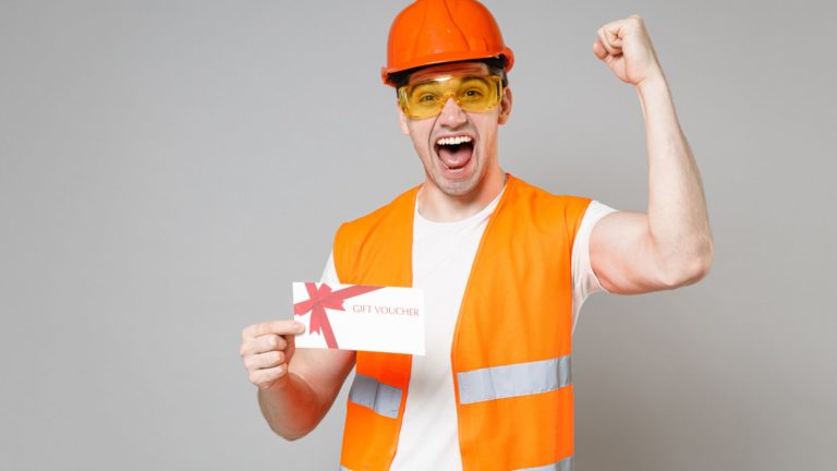 A happy worker celebrates with a gift voucher in his hand