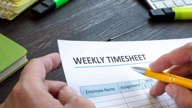 Closeup of an employee filling in a weekly timesheet with pen and paper instead of a mobile timesheet app