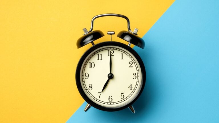 An old-timey alarm clock against a yellow and bright blue background