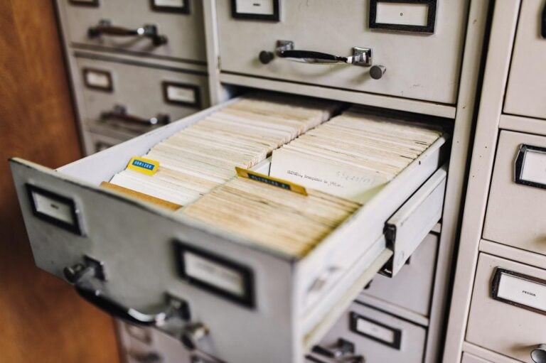 An open file cabinet drawer filled with yellowed documents