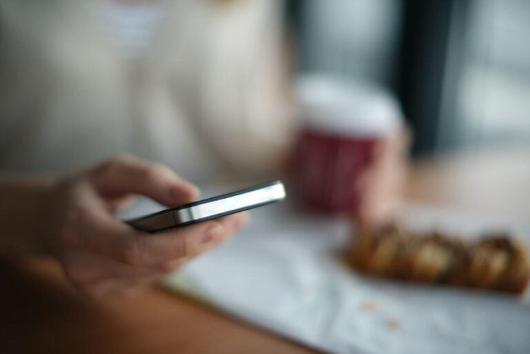 Image of a hand holding a smartphone to use an employee messaging system