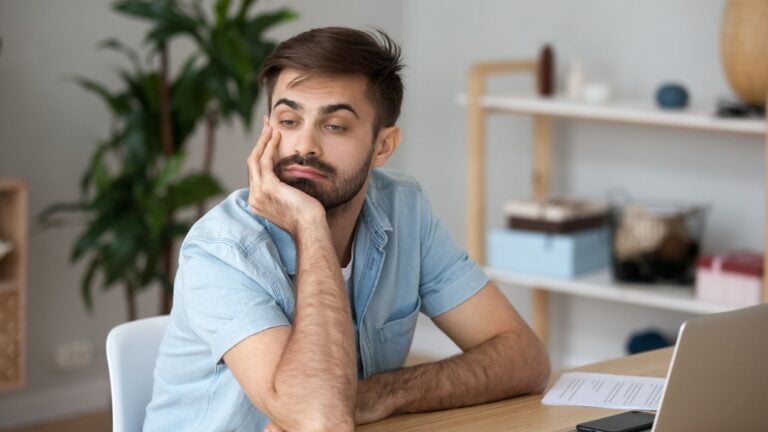 An unmotivated employee sits at their workstation with a bored expression on their face