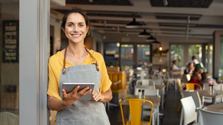 A smiling restaurant employee holding a tablet