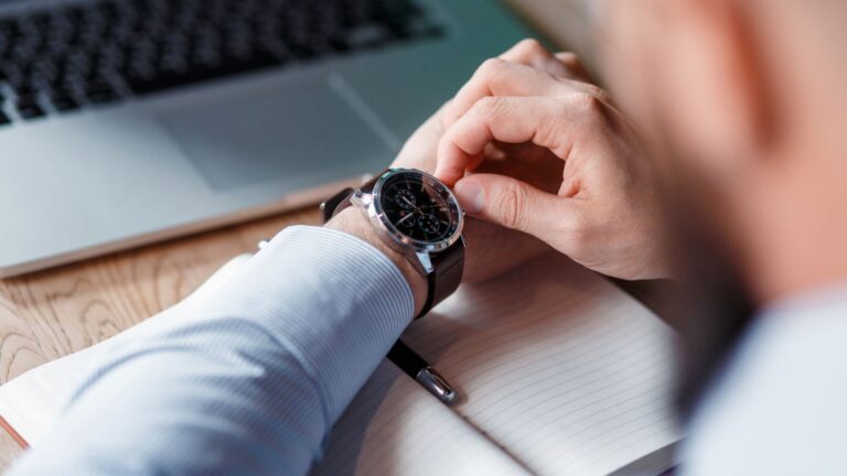 A worker checks his wristwatch in the office