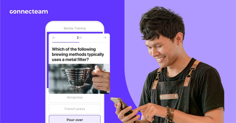A barista in an apron is looking at his Connecteam Training & Onboarding app on his phone.