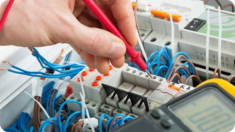 Electrician testing wiring in control panel