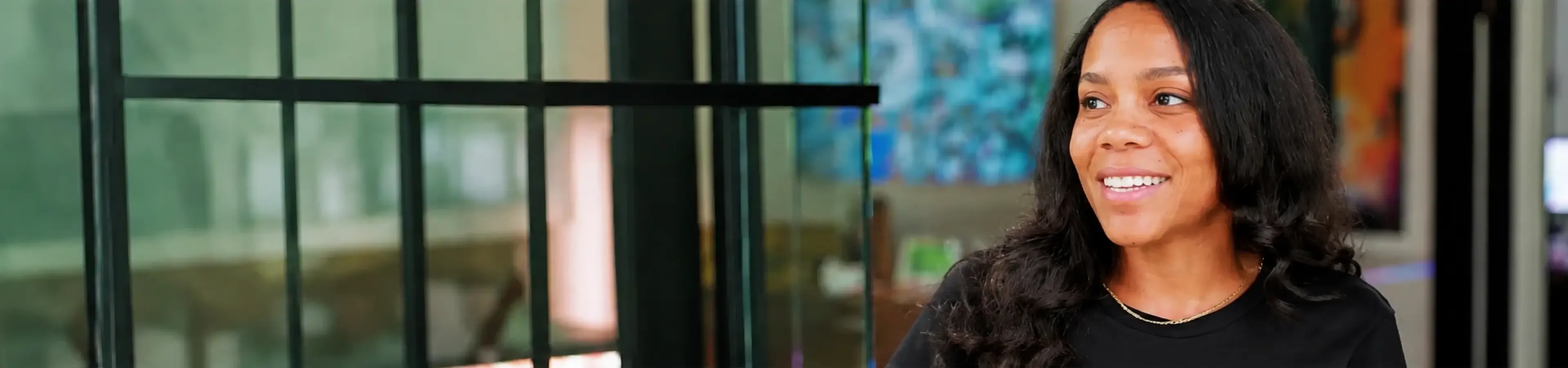 Woman in a black shirt smiling in a bright, modern space.